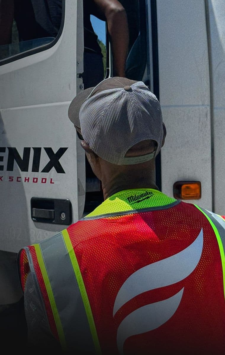 A Fenix student in a hi-vis vest climbing into the cab